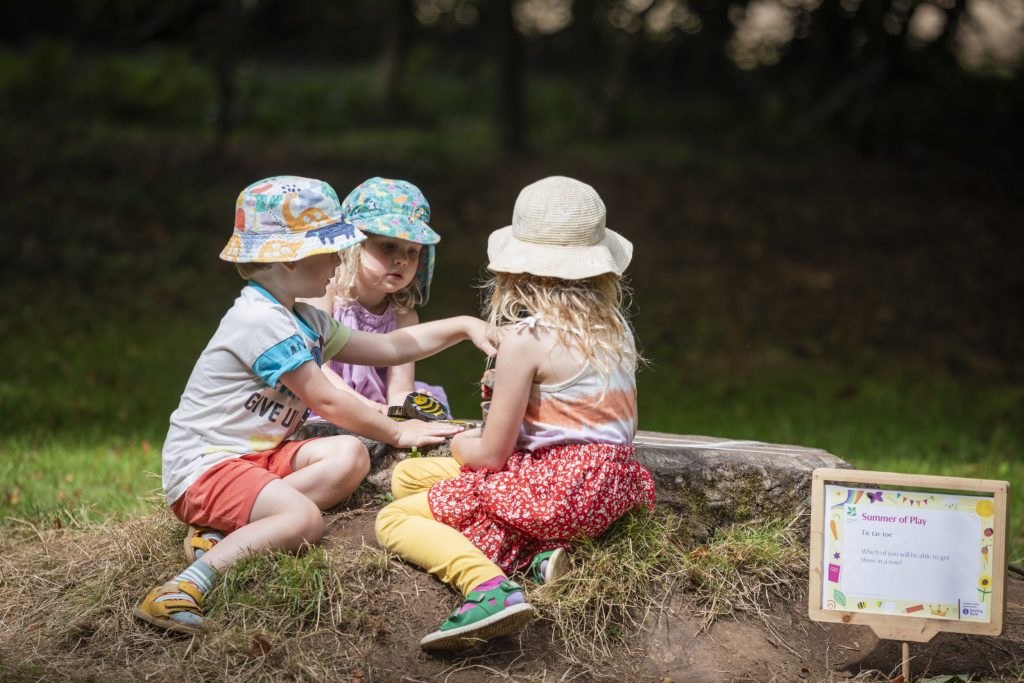 Children playing Tic Tac Toe on a tree stump at Trengwainton Garden, Cornwall