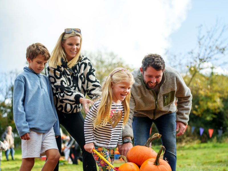 Family pushing pumpkins in wheelbarrow